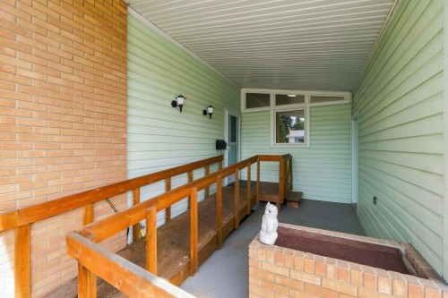 Covered entry with light green siding and brick accents - 9311 68 Street Nw, Edmonton, AB 