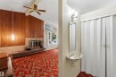 Vaulted ceiling with an exposed beam, a brick fireplace with a raised hearth, wood paneling, and an accordion-style closet door - 9311 68 Street Nw, Edmonton, AB 