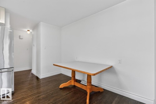 Dark wood-finish flooring with white baseboards, a stainless steel refrigerator, and a flush-mount ceiling light - 7304 98A Avenue Nw, Edmonton, AB 