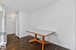 Dark wood-finish flooring with white baseboards, a stainless steel refrigerator, and a flush-mount ceiling light - 