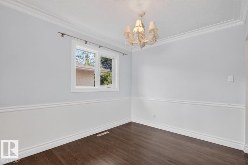 Dark wood-finish flooring, white chair rail molding, and a decorative chandelier - 7304 98A Avenue Nw, Edmonton, AB 