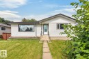 Front exterior with a white stucco finish, a black-framed picture window, and a gray shingled roof - 7304 98A Avenue Nw, Edmonton, AB 