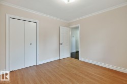 Wood-finish flooring, white bi-fold closet doors, white trim, white crown molding, and an overhead flush-mount light fixture - 