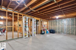 Unfinished basement featuring exposed wood beams, concrete flooring, and framed walls with insulation - 