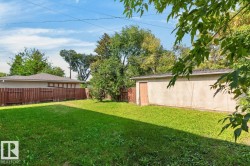 Expansive grassy yard with a detached garage structure and full privacy fencing - 
