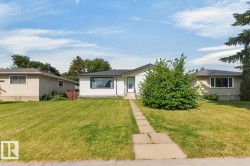 Front exterior featuring white siding, a dark shingle roof, a prominent picture window, and a concrete paver walkway - 