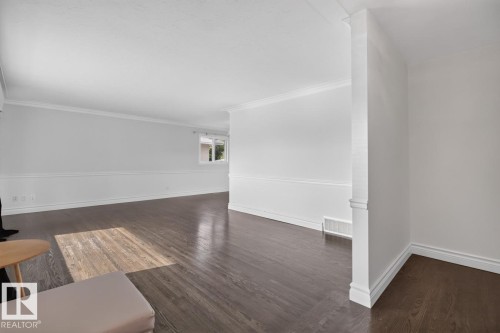 Dark wood-finish flooring, crown molding, chair rail detailing, white painted walls, and white trim - 7304 98A Avenue Nw, Edmonton, AB 