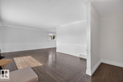 Dark wood-finish flooring, crown molding, chair rail detailing, white painted walls, and white trim - 