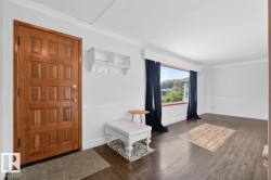 Wood-finish flooring, white crown molding, large picture window with deep sill, white wainscoting, and a paneled entry door - 