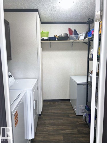 Laundry area featuring wood-finish flooring, overhead ceiling light, and wall-mounted shelving - 63 Willow Park Estates, Leduc, AB 