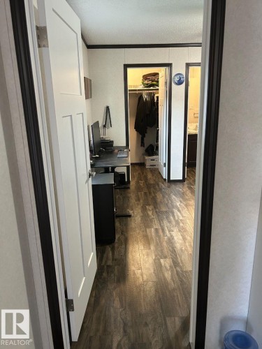Wood-finish flooring throughout, white interior doors with dark trim, and a built-in closet with shelving - 63 Willow Park Estates, Leduc, AB 