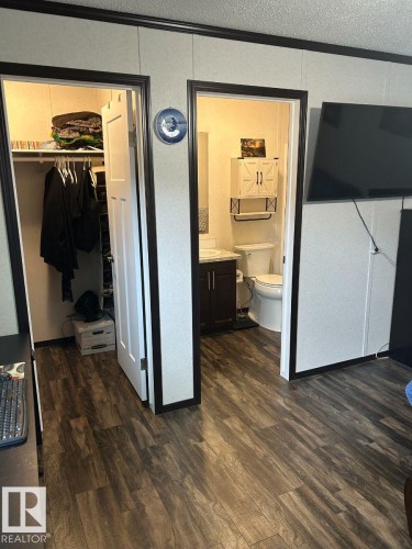 Wood-finish flooring throughout, a built-in closet with shelving and hanging rods, and a bathroom featuring a vanity with under-sink storage and a wall-mounted cabinet - 63 Willow Park Estates, Leduc, AB 