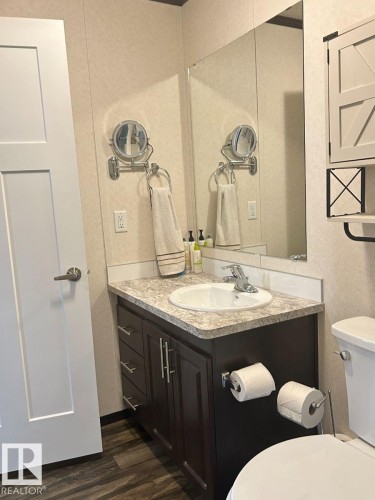Dark wood-finish vanity with a built-in sink and a patterned countertop - 63 Willow Park Estates, Leduc, AB 
