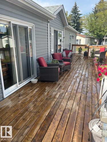 Expansive composite deck with rich wood-finish flooring and built-in seating areas, offering multiple zones for entertaining - 63 Willow Park Estates, Leduc, AB 