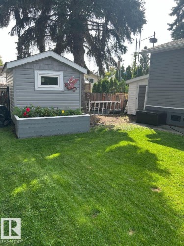 Shed with horizontal gray siding and white trim, featuring a rectangular window - 63 Willow Park Estates, Leduc, AB 