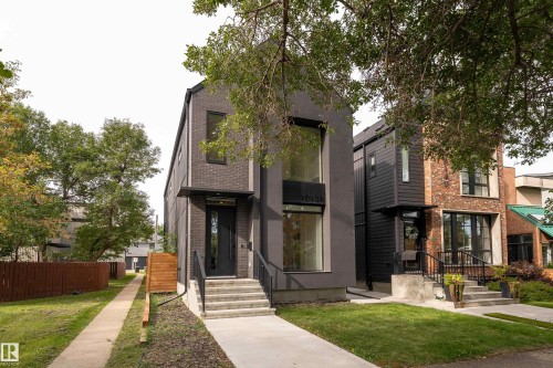 Modern facade featuring dark brick and smooth paneling, large windows, and a prominent front entry with an awning - 10138 90 Street Nw, Edmonton, AB 