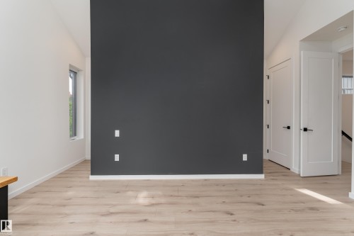 Vaulted ceiling, light wood-finish flooring, accent wall, modern interior doors, and a rectangular window - 10138 90 Street Nw, Edmonton, AB 