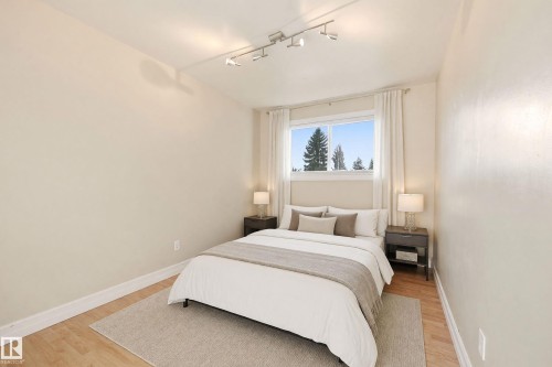 Light wood-finish flooring, white window trim, and a ceiling-mounted track light fixture - 3523 106 Street Nw, Edmonton, AB 
