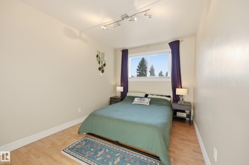 Bright room with wood-finish flooring, a window offering exterior scenery, and a track lighting fixture - 3523 106 Street Nw, Edmonton, AB 