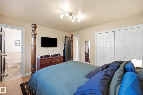 Wood-finish flooring, track lighting fixture, and white sliding closet doors - 3523 106 Street Nw, Edmonton, AB 