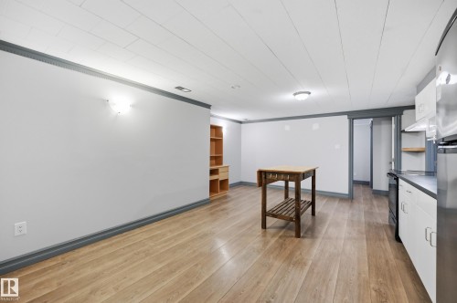 Wood-finish flooring, white paneled ceiling, recessed lighting, wall-mounted sconce, and built-in shelving - 3523 106 Street Nw, Edmonton, AB 