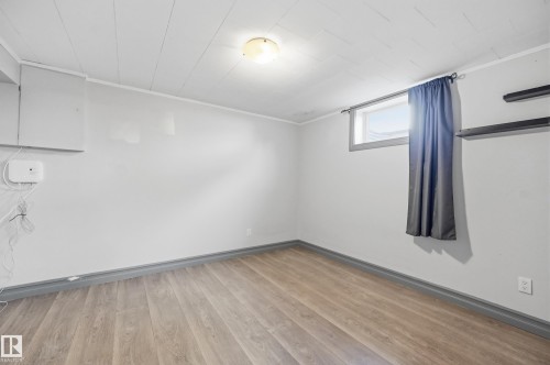 Wood-finish flooring with coordinating baseboards, neutral wall paint, and a built-in light fixture - 3523 106 Street Nw, Edmonton, AB 