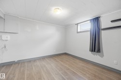 Wood-finish flooring with coordinating baseboards, neutral wall paint, and a built-in light fixture - 