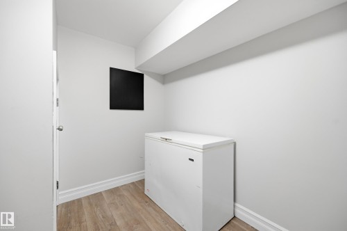 Light wood-finish flooring, white walls, and a white door with a round knob - 3523 106 Street Nw, Edmonton, AB 