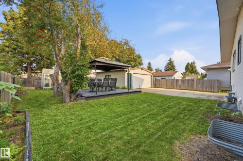 Expansive backyard featuring a manicured lawn, a wooden deck with a gazebo, a detached garage, and perimeter fencing - 3523 106 Street Nw, Edmonton, AB 