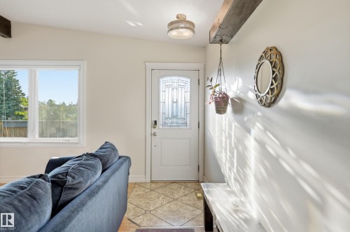 Entryway featuring a white door with decorative glass inserts, overhead flush mount lighting, a prominent exposed wood beam, and ceramic tile flooring - 3523 106 Street Nw, Edmonton, AB 