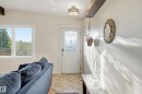 Entryway featuring a white door with decorative glass inserts, overhead flush mount lighting, a prominent exposed wood beam, and ceramic tile flooring - 3523 106 Street Nw, Edmonton, AB 