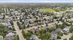 Expansive residential area with numerous detached properties, abundant mature trees, and a visible recreational field - 