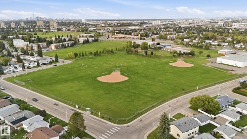 Expansive green space featuring multiple baseball diamonds and soccer fields, surrounded by residential properties and a distant city skyline - 3523 106 Street Nw, Edmonton, AB 