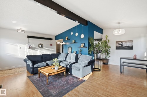 Wood-finish flooring, exposed ceiling beams, recessed and pendant lighting, and a painted accent wall - 3523 106 Street Nw, Edmonton, AB 