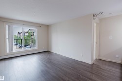 Open-concept living space featuring wood-finish flooring, neutral wall tones, and white baseboards - 