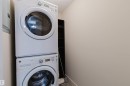Laundry area featuring a stacked washer and dryer, light-toned wall paint, and a textured ceiling - #304 6084 Stanton Dr Sw, Edmonton, AB  - Indoor Photo Showing Laundry Room 