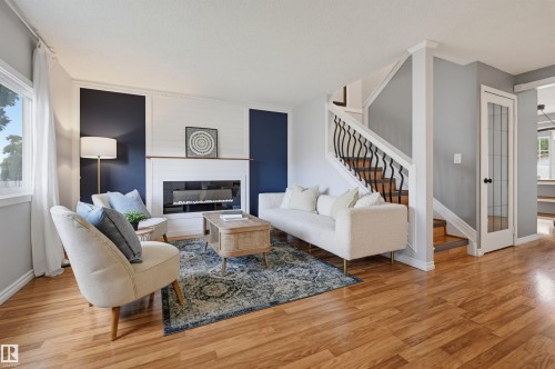 Wood-finish flooring, staircase with decorative wrought iron balusters, built-in fireplace, and white trim accents - 4125 38 Street Nw, Edmonton, AB 