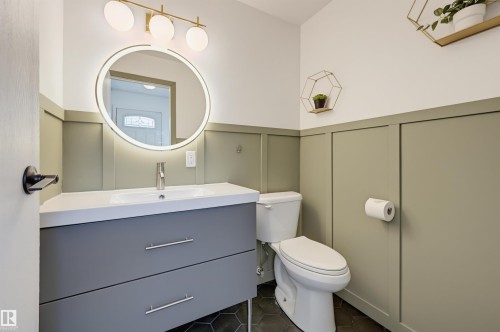 Modern vanity with an integrated sink and brushed nickel faucet, illuminated by a backlit circular mirror - 4125 38 Street Nw, Edmonton, AB 