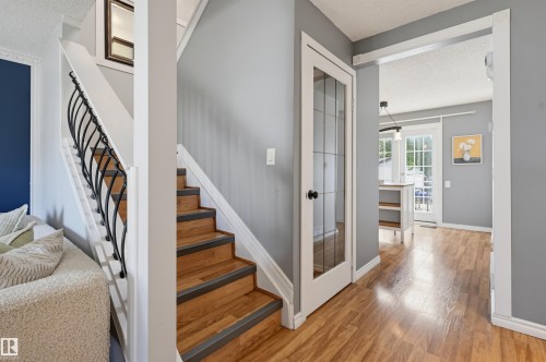 Hardwood-finish flooring, staircase with wrought iron railing, white trim, glass-paneled door, and recessed lighting - 4125 38 Street Nw, Edmonton, AB 