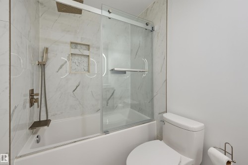 Bathtub with integrated shower, glass sliding shower door, recessed shower niche, and wall-mounted shower fixtures - 4125 38 Street Nw, Edmonton, AB 