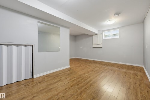 Expansive room featuring wood-finish flooring, a contemporary ceiling light fixture, and a built-in wall cabinet - 4125 38 Street Nw, Edmonton, AB 