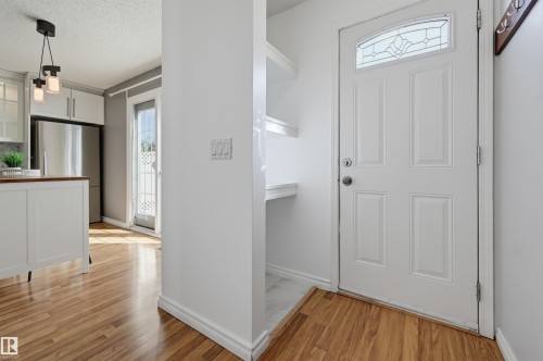 Wood-finish flooring throughout, white paneled door with decorative glass insert, and built-in shelving - 4125 38 Street Nw, Edmonton, AB 
