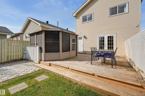 Expansive wood deck with dual French doors, a screened-in gazebo, and a paved patio area - 4125 38 Street Nw, Edmonton, AB 
