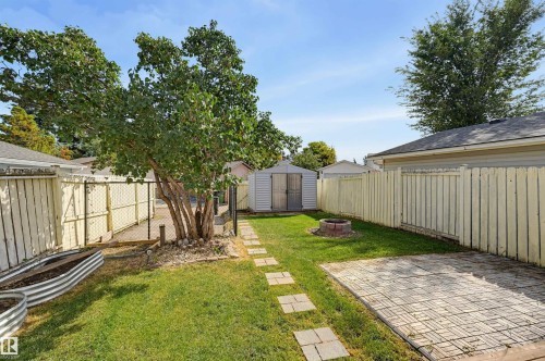 Fenced yard with a paved patio area, stepping stone pathway, and a detached storage shed - 4125 38 Street Nw, Edmonton, AB 