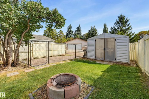 Grassed yard with a fire pit, chain link fencing, a white storage shed, and a privacy fence - 4125 38 Street Nw, Edmonton, AB 
