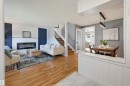 Wood-finish flooring throughout, modern fireplace with white mantel, custom staircase with wrought iron detailing, built-in dining area lighting, and a glass-paneled interior door - 4125 38 Street Nw, Edmonton, AB 