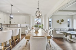 Open-concept living space with dark wood-finish flooring, white coffered ceiling, and pendant light fixtures - 