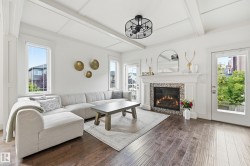 Wood-finish flooring, coffered ceiling, built-in fireplace with tile surround, white trim, and a built-in light fixture - 