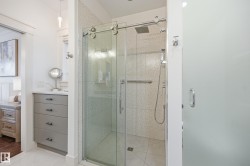 Glass-enclosed shower with a rainfall showerhead, handheld shower fixture, and a built-in grab bar - 