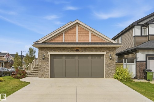 Stone-clad exterior featuring a two-car garage with a concrete driveway - 1961 Adamson Terrace Sw, Edmonton, AB 
